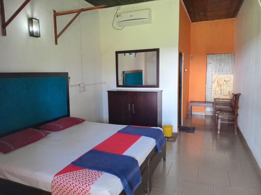 a bedroom with a bed and a mirror and a chair at Ceylonica Beach Hotel in Negombo