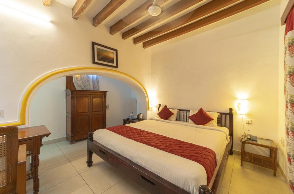 a bedroom with a bed and a desk in a room at Dumas Guest House in Puducherry