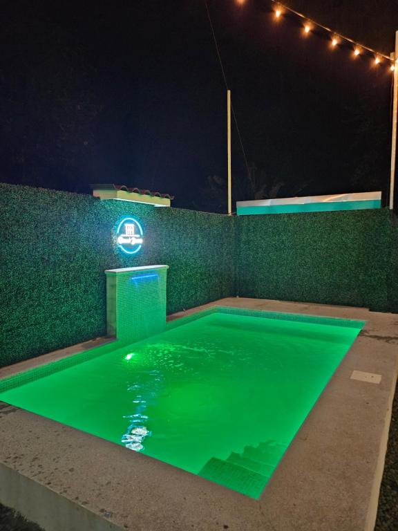 una piscina con iluminación verde por la noche en Ocean's Breeze Apartment and Rooms, en Puerto Viejo