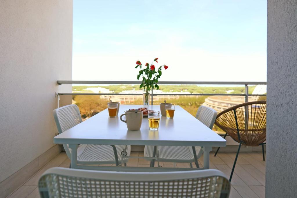einen Tisch mit Getränken und Blumen auf dem Balkon in der Unterkunft Nice studio with view in La Grande Motte - Welkeys in La Grande-Motte
