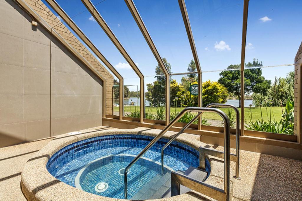 an indoor hot tub in a house with windows at Lakeside Country Club in Numurkah