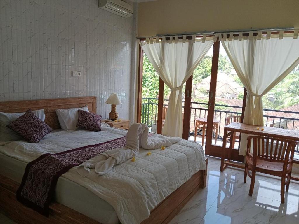 a bedroom with a large bed and a balcony at INJIHAR HOUSE in Ubud