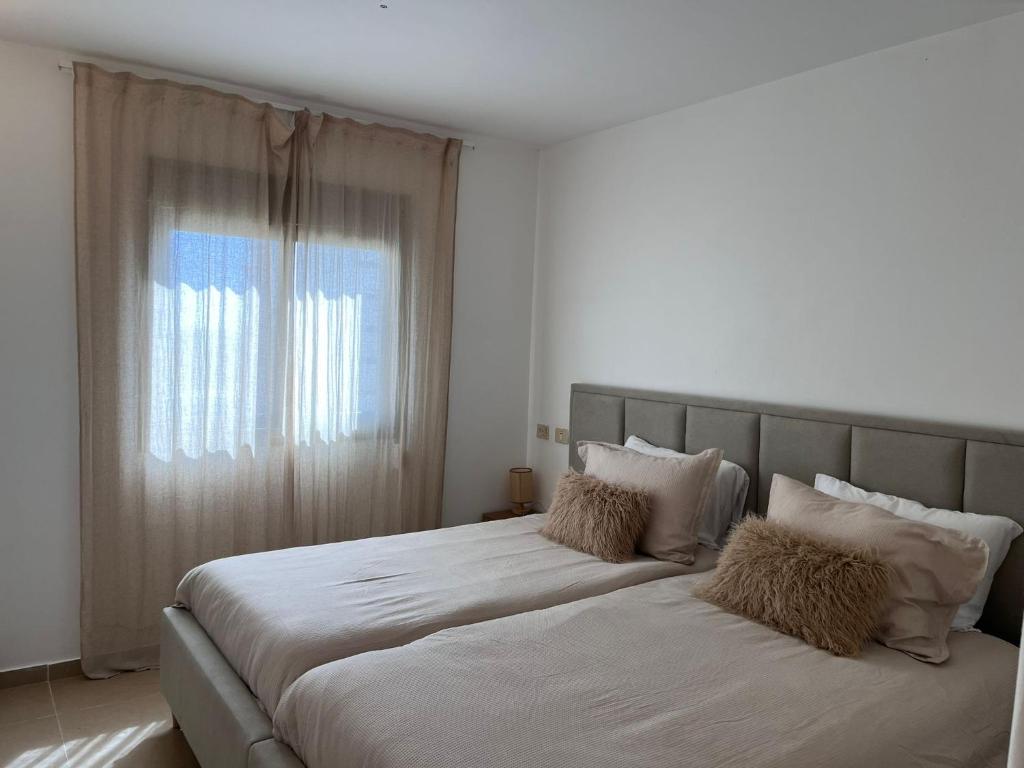 two beds in a white room with a window at Beach Front Apartment in Netanya