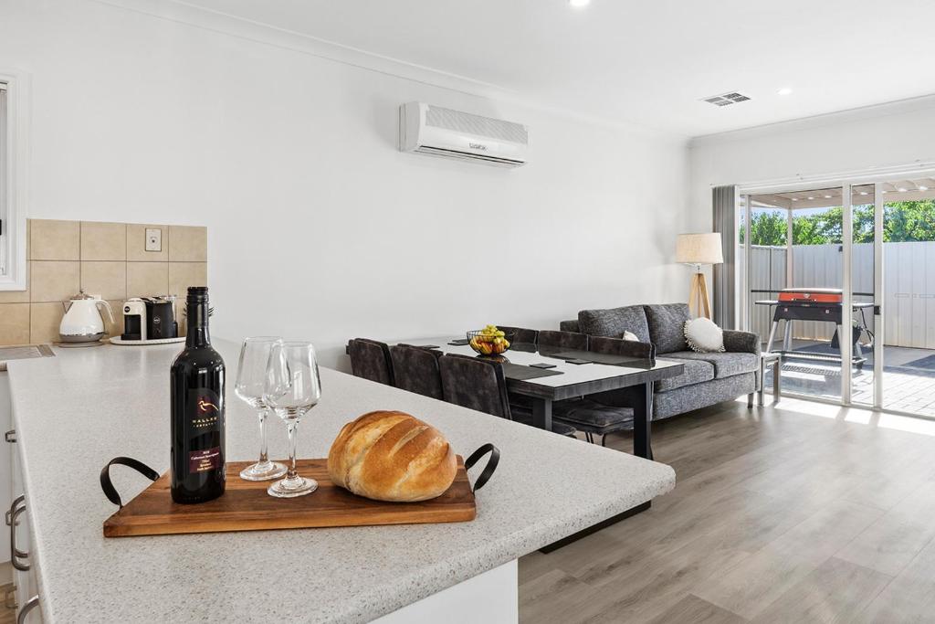 a bottle of wine and a loaf of bread on a kitchen counter at Shamrock House C in Renmark