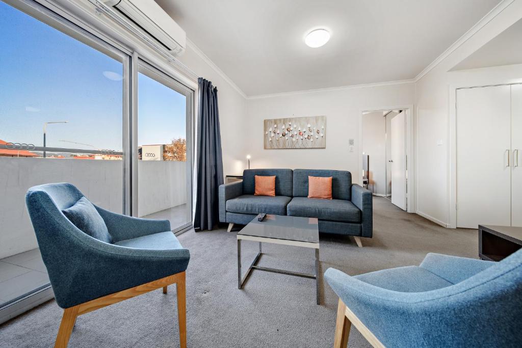 a living room with two blue chairs and a couch at Comfy Lakeside 1-Bed with Secure Parking in Tuggeranong