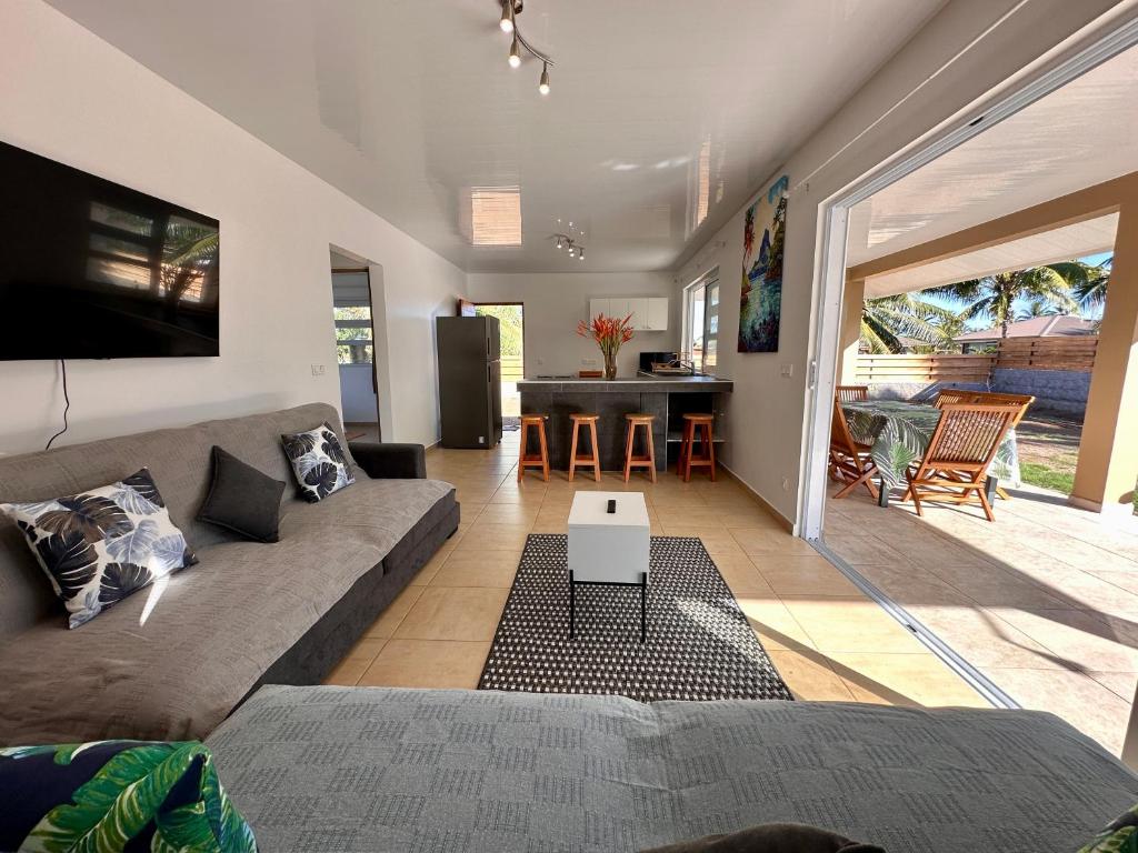 uma sala de estar com um sofá e uma mesa em Maison Te Manu - plage privée avec vue sur Tahiti à quelques pas em Maatea