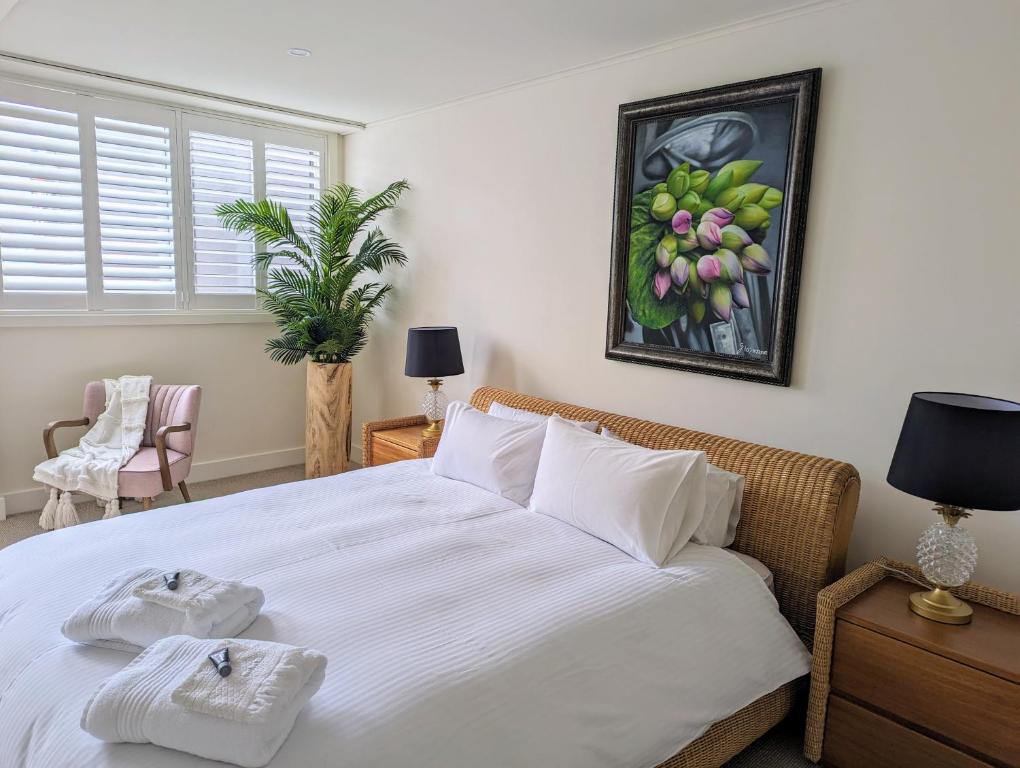 a bedroom with a large white bed with towels on it at ONE Luxury Apartment in Devonport