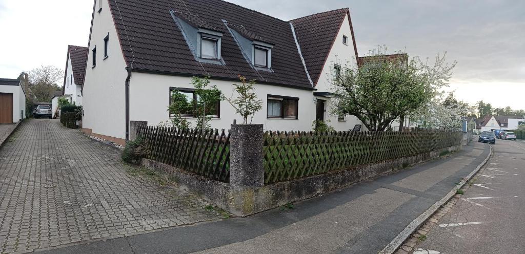 a white house with a black roof and a fence at Möbliertes Zimmer in Nuremberg