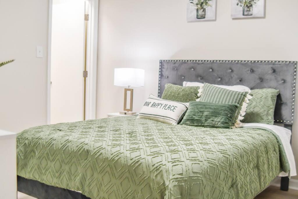 1 dormitorio con 1 cama con edredón y almohadas verdes en Serene Condo W/ LED Lights In Heart Of Raleigh en Raleigh