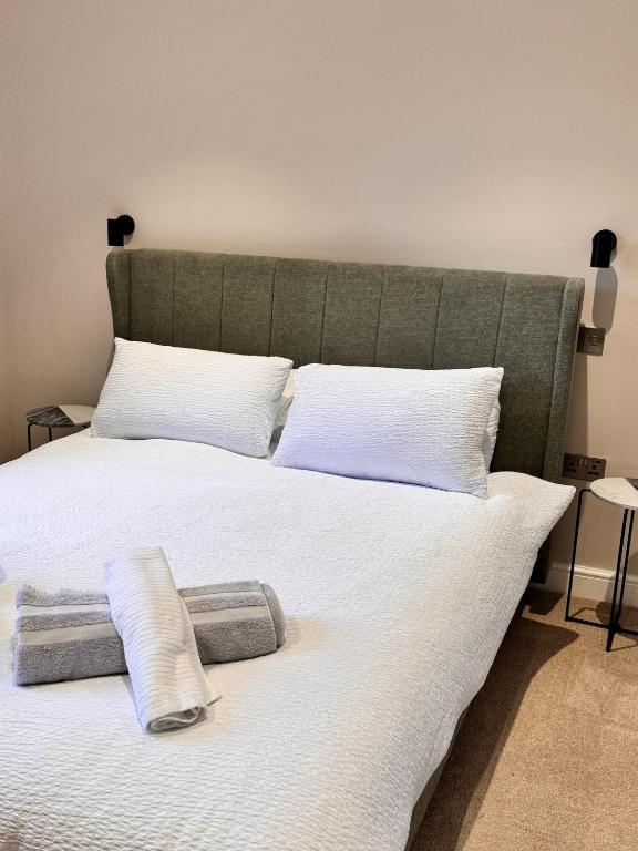 uma cama grande com lençóis brancos e almofadas em Luxury Leeds City Centre 1 Bedroom Flat em Leeds
