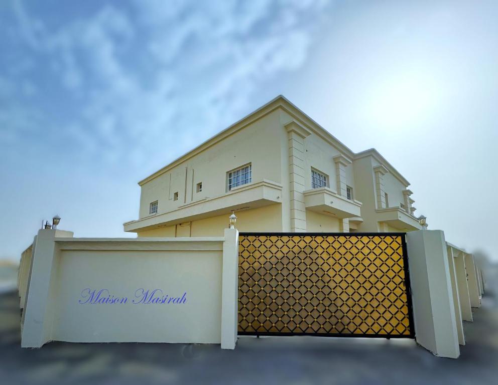 a yellow house behind a white fence at Maison Masirah in Şūr Maşīrah