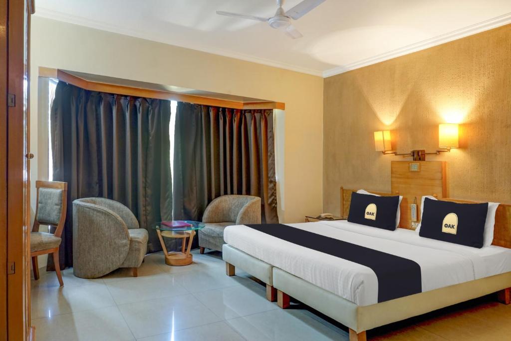 a bedroom with a bed and chairs in a room at Super Townhouse Oak Orchard Hotel in Pune