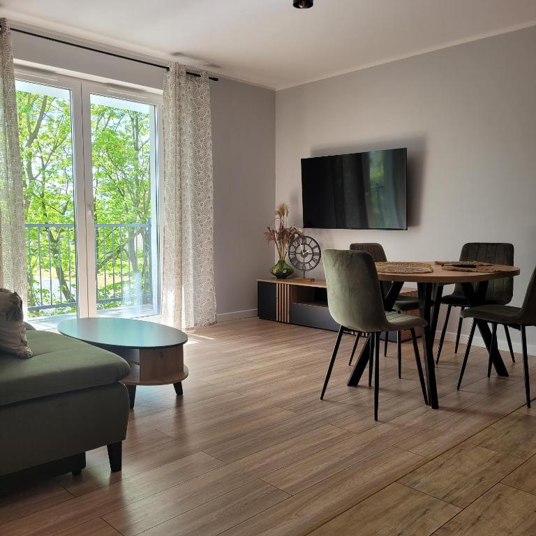 sala de estar con mesa, sillas y TV en NATURA apartament en Malbork