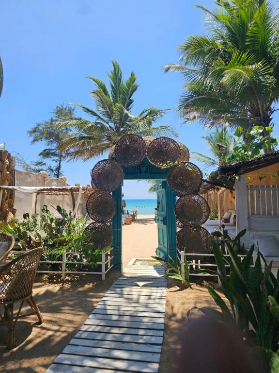 Zugang zu einem Strand mit einer grünen Tür und Palmen in der Unterkunft Memo's Beach in Nilaveli