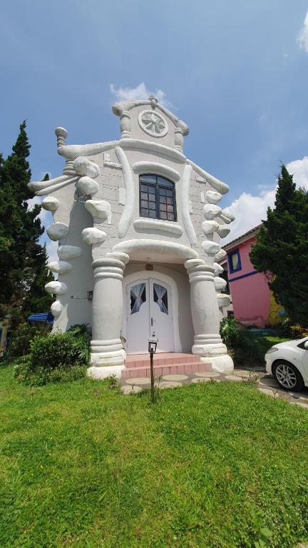 une grande maison blanche avec une horloge. dans l'établissement Villa Panda N Kota Bunga Puncak, à Cikundul