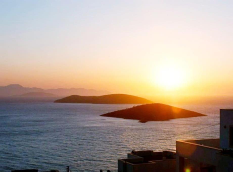 um pôr-do-sol sobre um corpo de água com uma ilha em Seaview (Sunset & Greek-Islands) Luxury Apartment em Bodrum City