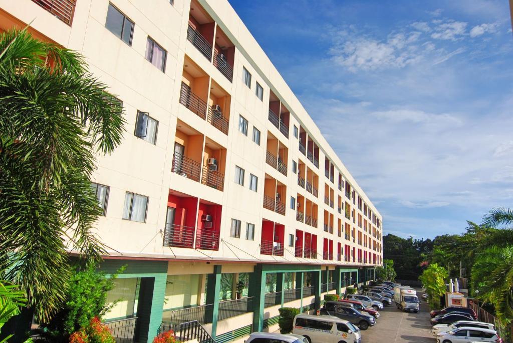 ein großes Gebäude mit Autos auf einem Parkplatz in der Unterkunft The Uptown Place Condominium in Iloilo City