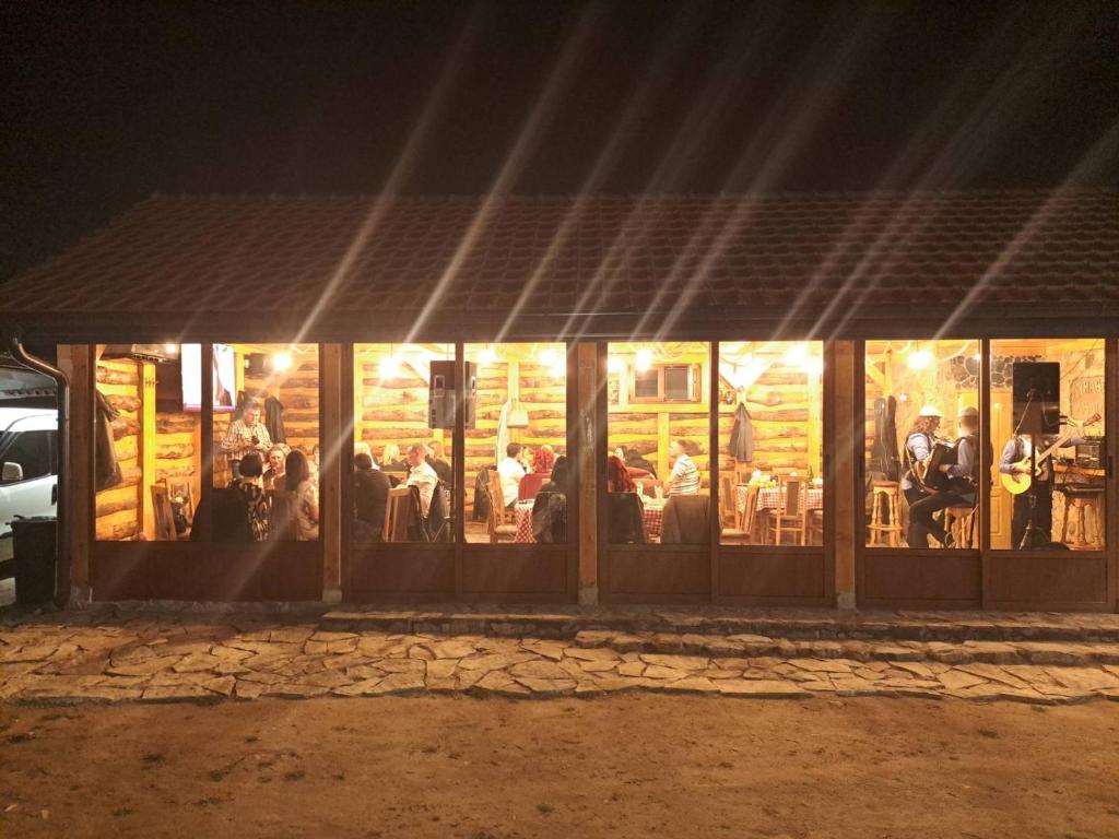 een groep mensen die 's nachts buiten een restaurant zitten bij Dunavska Avlija in Mala Vrbica