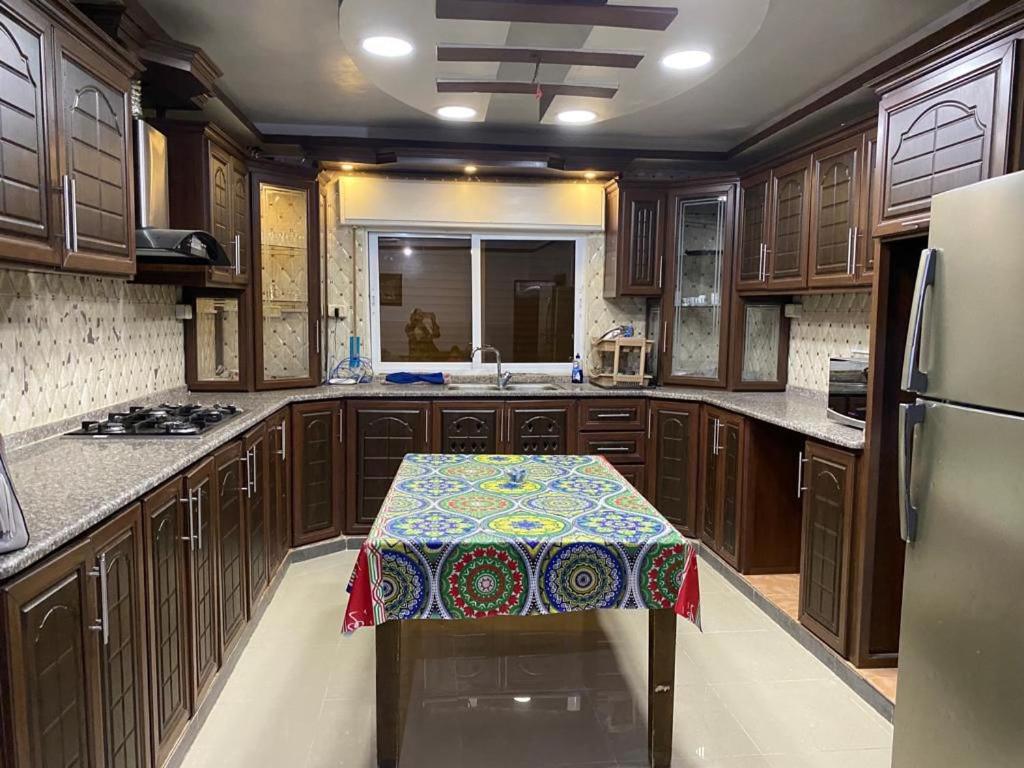 uma cozinha com armários de madeira e uma mesa com um padrão em شقة مفروشة للايجار em Irbid