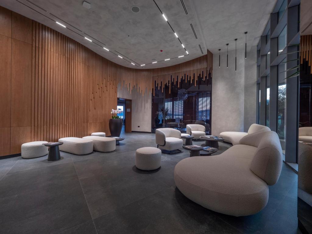 a lobby with white chairs and tables and windows at Sea Star Budva in Budva