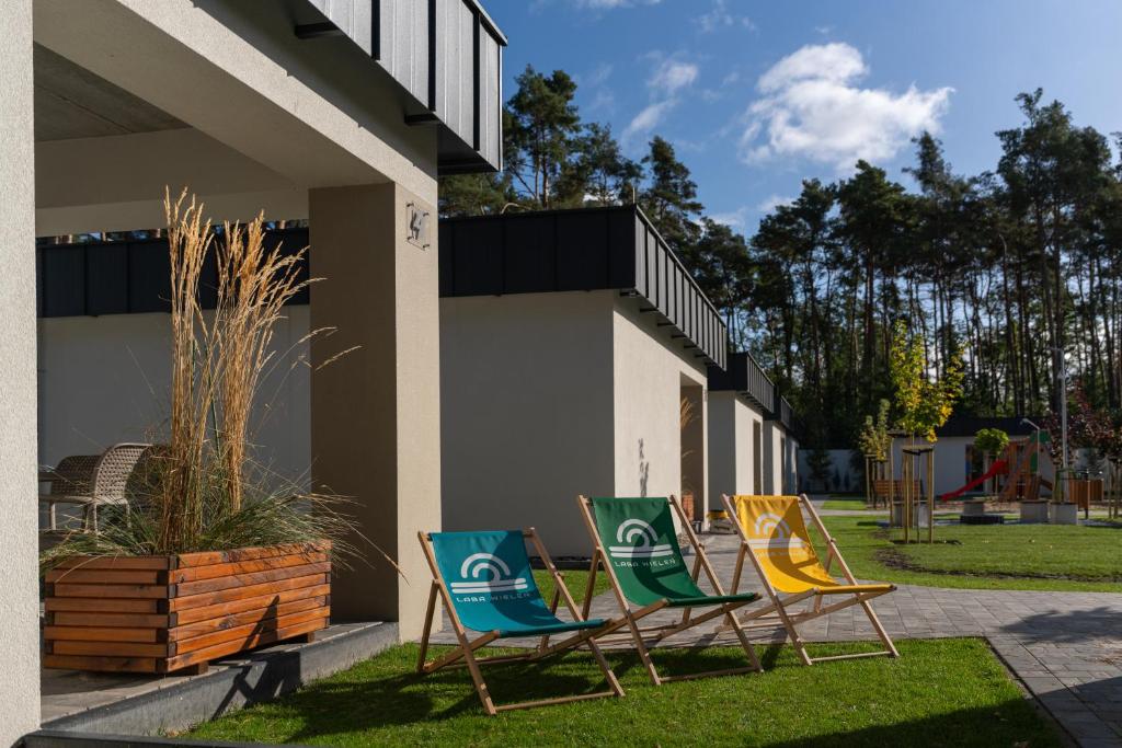 three chairs sitting in the grass next to a building at LABA Wieleń in Wielen Zaobrzanski