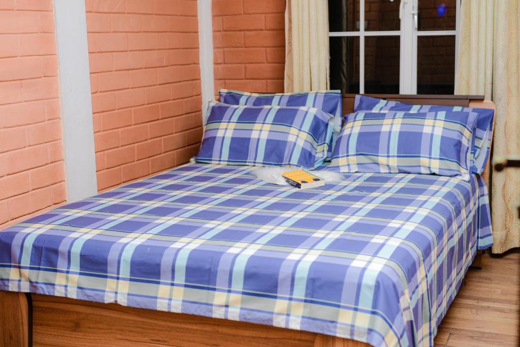 Una cama con sábanas de cuadros azules y blancos y una ventana. en Grashia Guest, en Nuwara Eliya