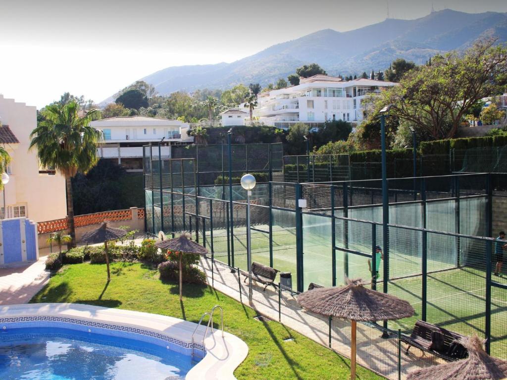 a swimming pool with umbrellas and a tennis court at Penthouse Apartment in Benalmadena in Benalmádena