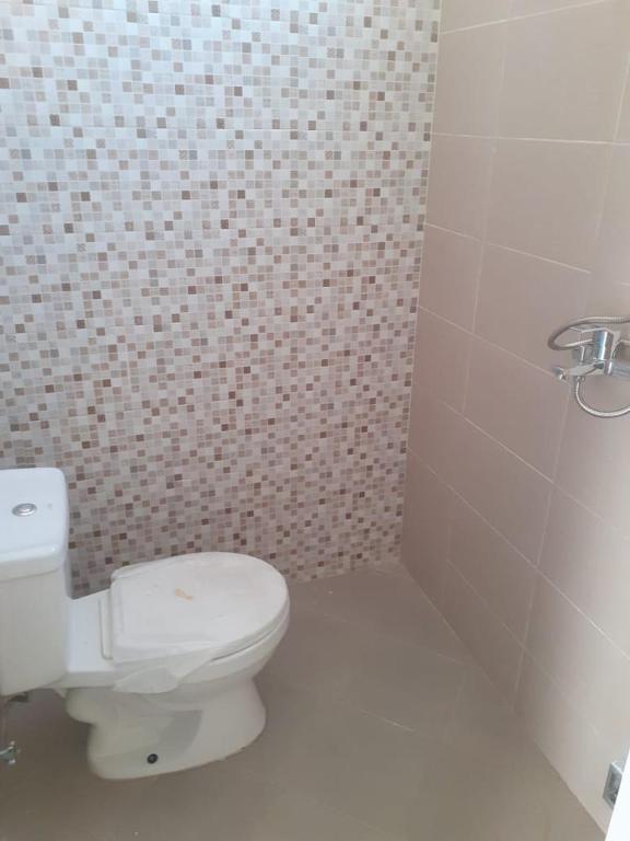a bathroom with a white toilet and a tiled wall at Cordoba residence F5 in Tlekung