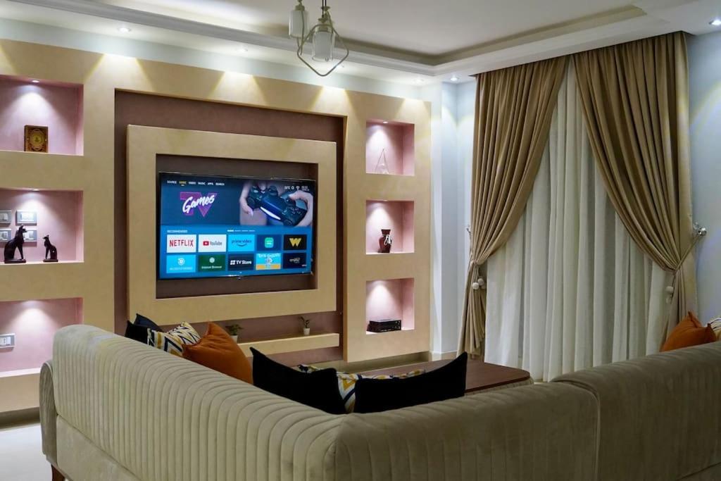 ein Wohnzimmer mit einem Sofa und einem Flachbild-TV in der Unterkunft Central/3 bed/Private & Equipped in Madinat as-Sadis min Uktubar