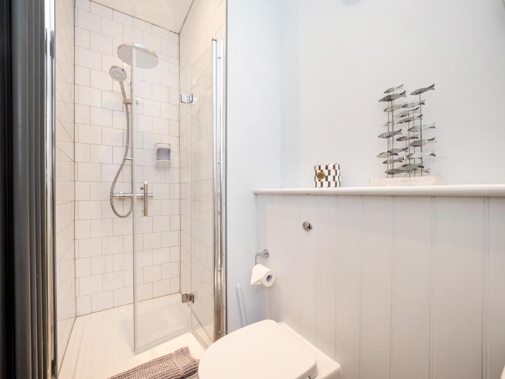 a white bathroom with a shower and a toilet at The Sands Sheringham in Sheringham