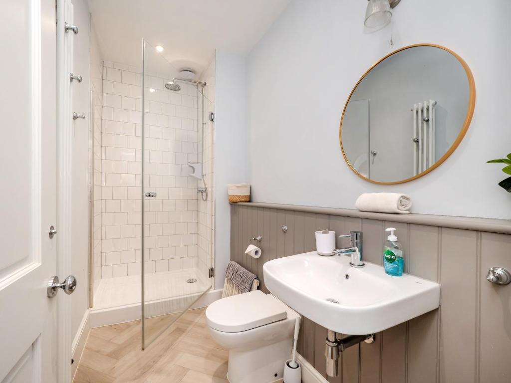 a bathroom with a sink and a toilet and a mirror at The Sands Sheringham in Sheringham