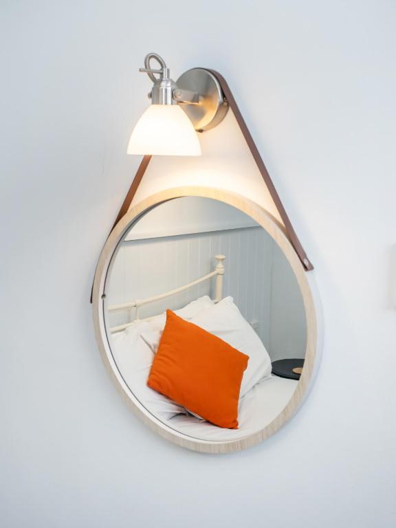 a mirror hanging on a wall with a orange pillow at The Sands Sheringham in Sheringham