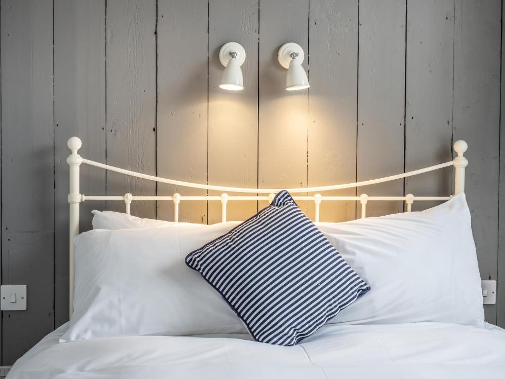 ein Bett mit weißer Bettwäsche und einem blauen und weißen Kissen in der Unterkunft The Sands Sheringham in Sheringham