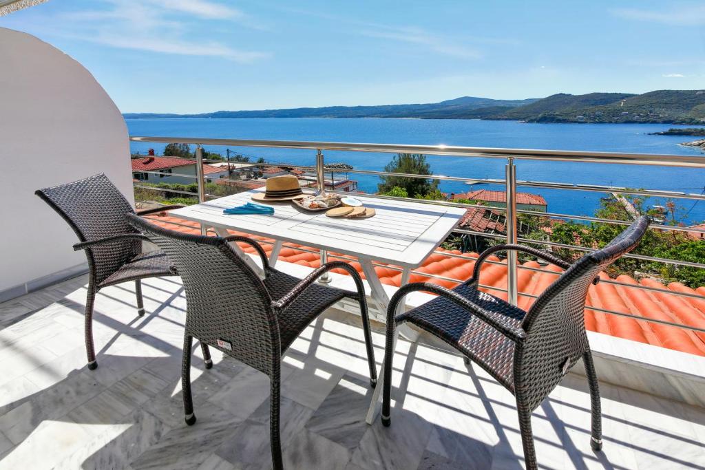 a table and chairs on a balcony with a view of the water at Thea Studios in Pyrgadikia