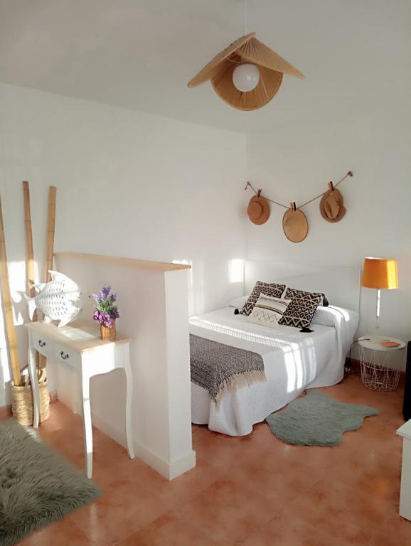 a white bedroom with a bed and a table at Apartamento entero con jardín en Casa Amelia in Padrón