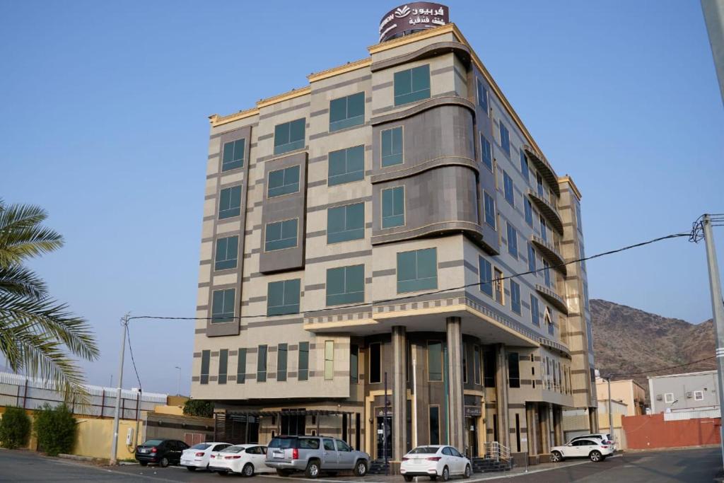 un edificio alto con macchine parcheggiate di fronte di شقق فربيون الفندقية -محايل a Muhayil