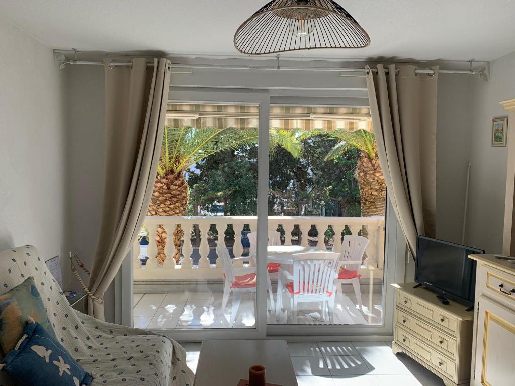 een woonkamer met een glazen schuifdeur met een tafel en stoelen bij Le Tropical in Fréjus