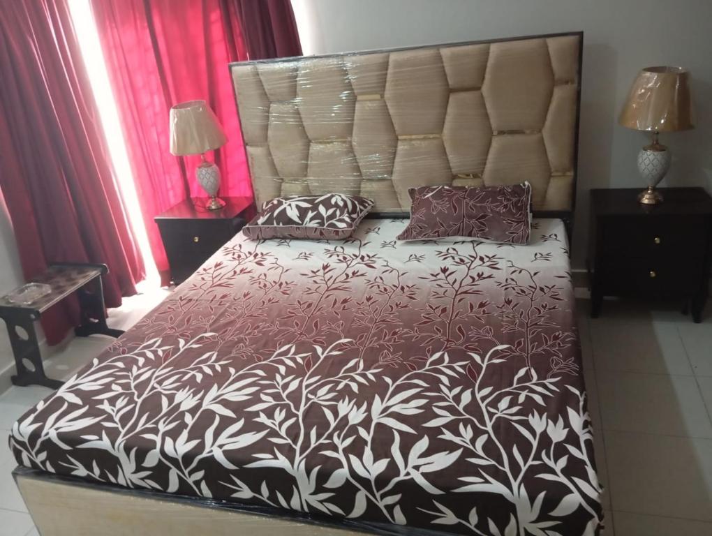 a bedroom with a large bed with a black and white bedspread at Balqees Cottage in Lahore