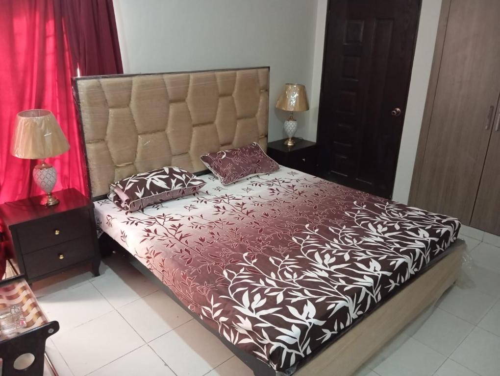 um quarto com uma cama grande com lençóis e almofadas vermelhos e brancos em Balqees Cottage em Lahore