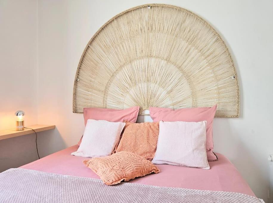 uma cama com almofadas cor-de-rosa e brancas e uma grande cabeceira de cama. em L'atelier, T3 central, calme et charme em Vincennes