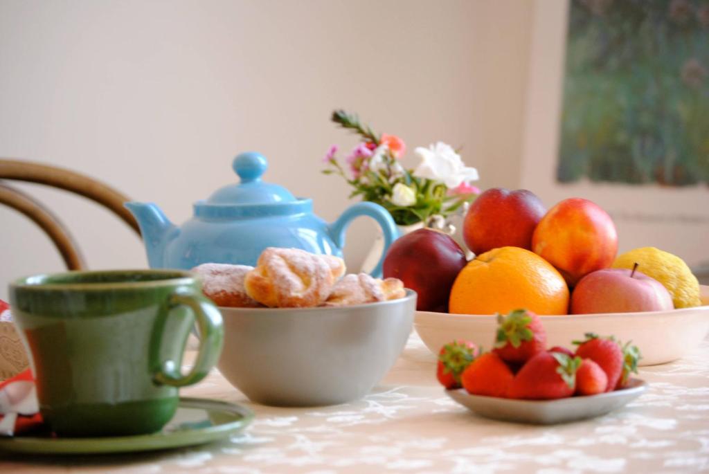 a table with bowls of fruit and cups on it at B&B Agapantus in una Villa dell'800 in Dolceacqua