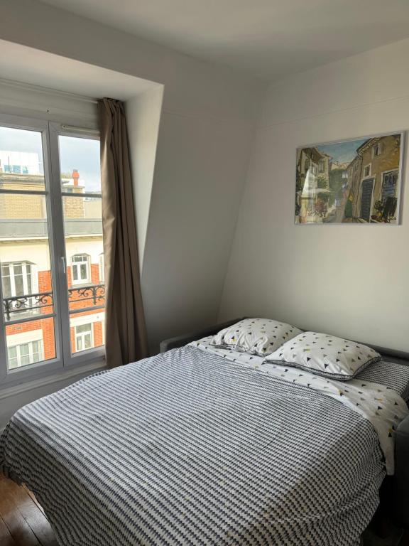 une chambre avec un lit et une grande fenêtre dans l'établissement Charmant Studio 5min de Paris, à Levallois-Perret