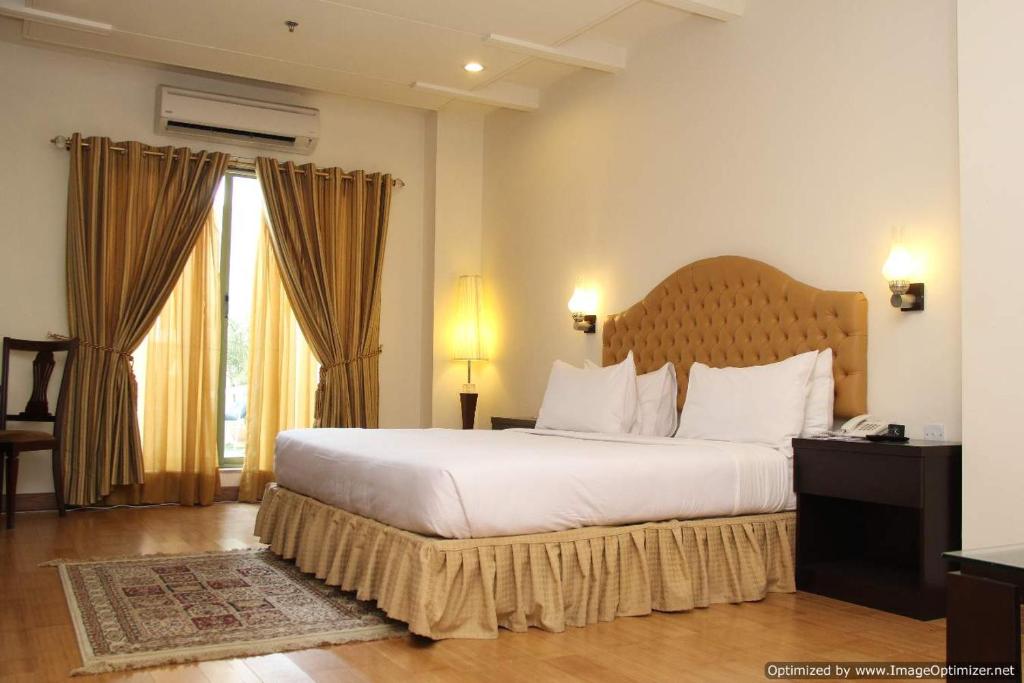 a bedroom with a large bed and a large window at Hotel Javson in Sialkot