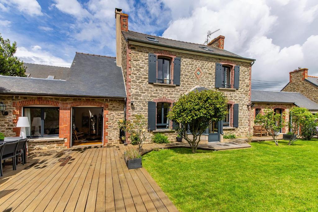 une maison avec une terrasse en bois dans la cour dans l'établissement CLOS HILY - Maison d'exception à Dinard - 10 pers, à Dinard