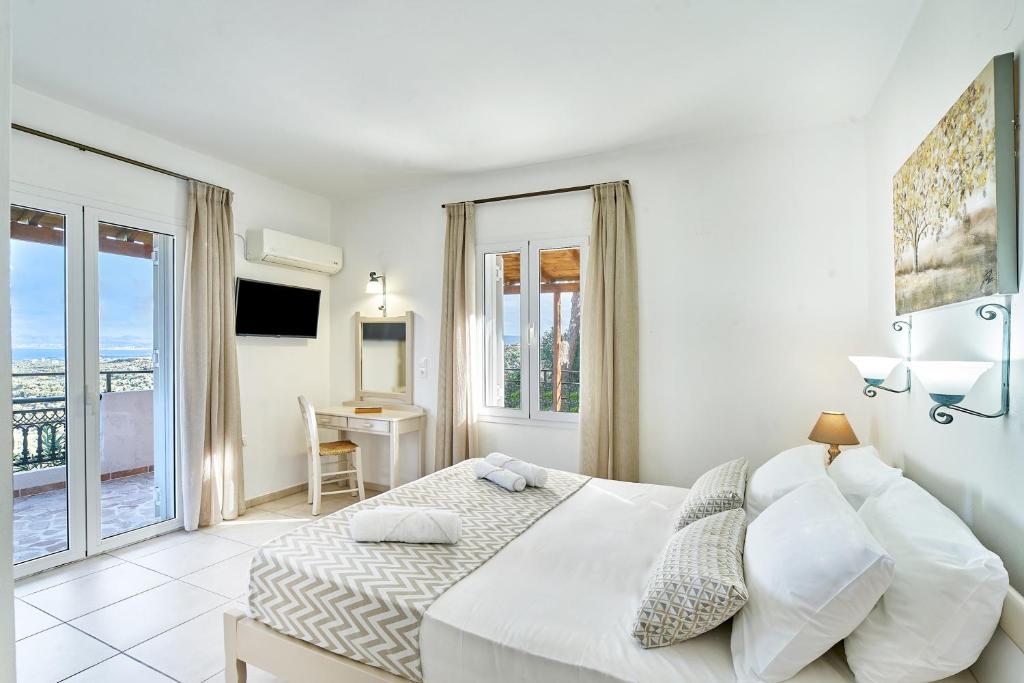 a white bedroom with a bed and a desk at Pano Stalos Villas in Stalos