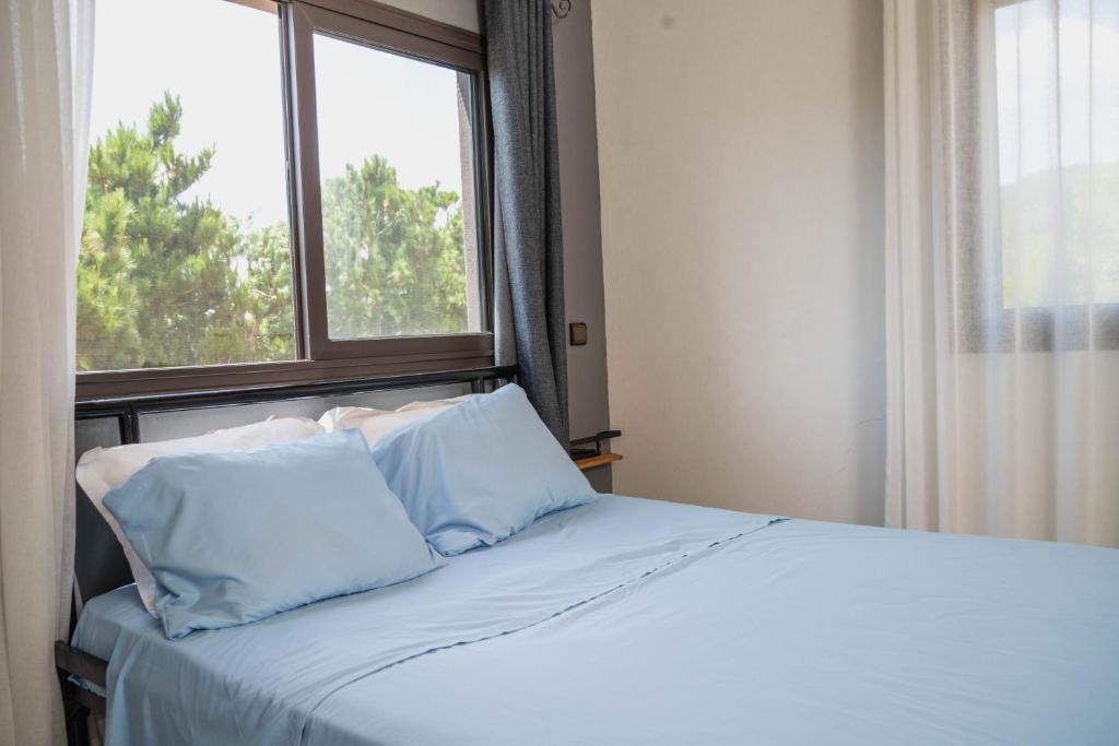 Come IN Hôtel في Imerintsiatosika: سرير مع وسائد زرقاء أمام النافذة