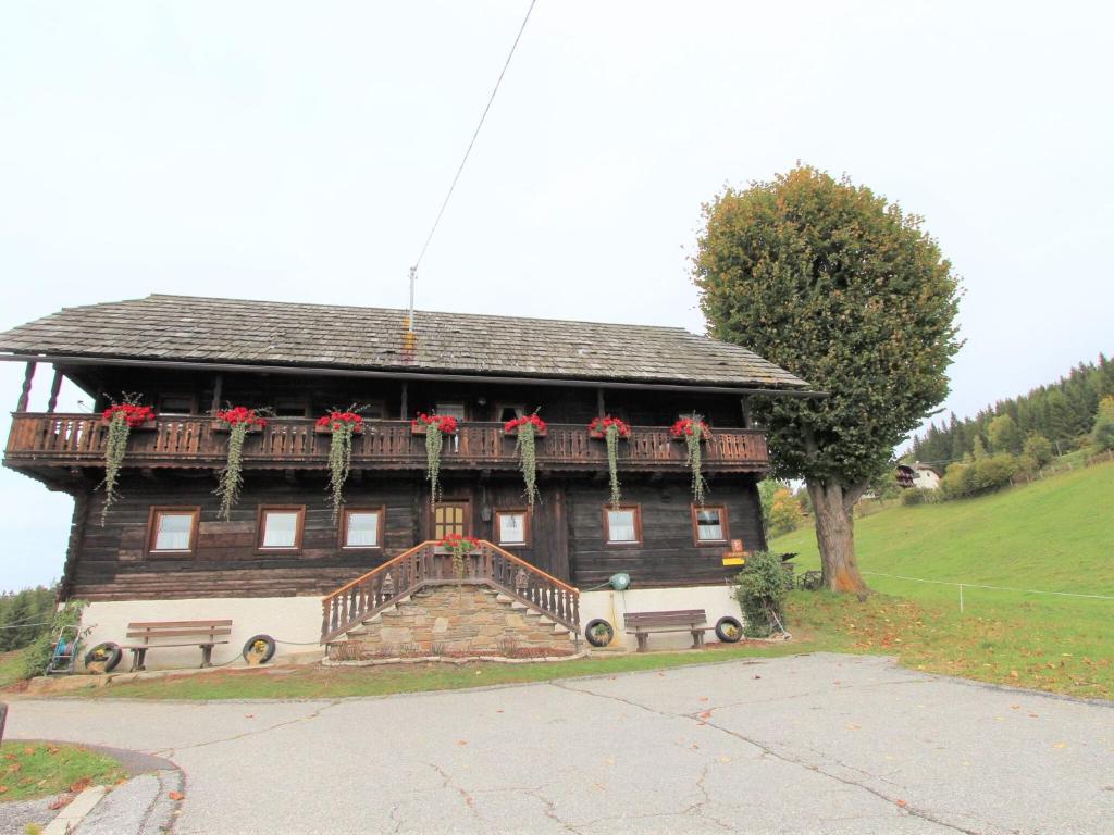 a large wooden house with red flowers on it at Characterful old farmhouse with 4 apartments in Fresach Carinthia with garden in Fresach