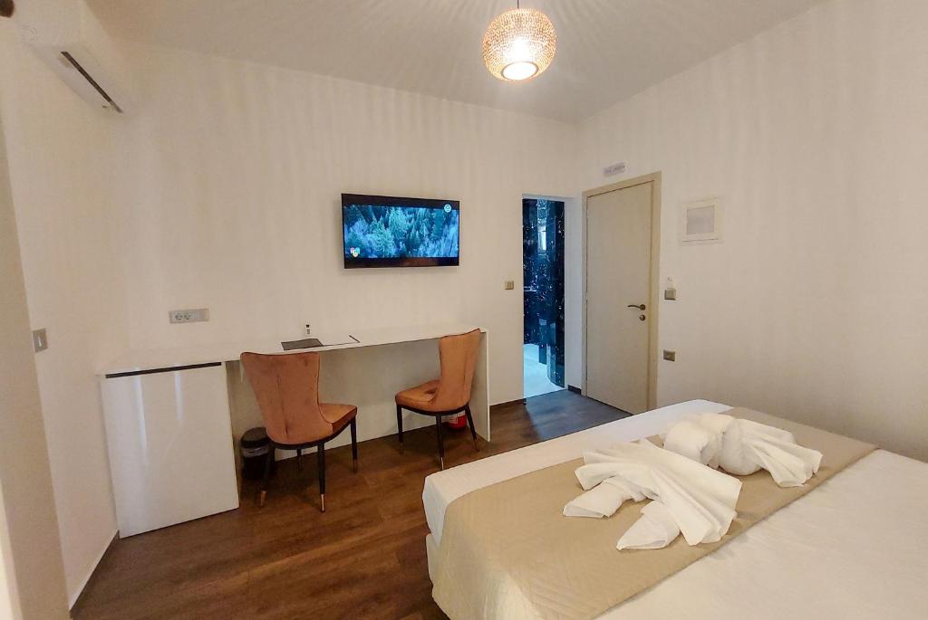 a bedroom with a bed and a desk with chairs at POLYMNIA III LUXURY APARTMENT ARGOSTOLI in Argostoli
