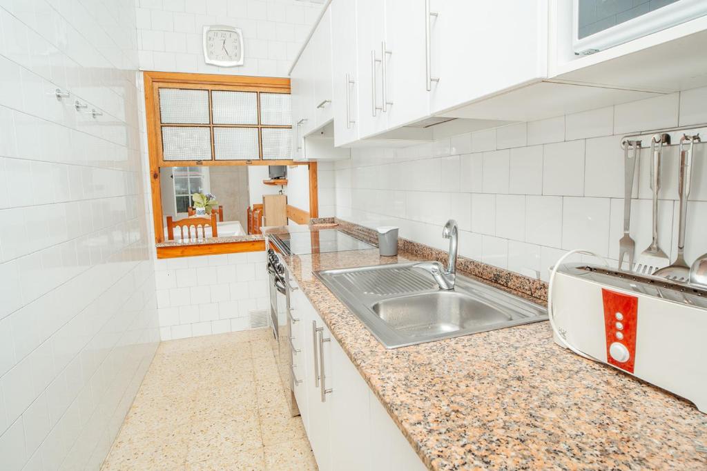 cocina blanca con fregadero y ventana en Apartamentos Ancoradoiro en Lariño