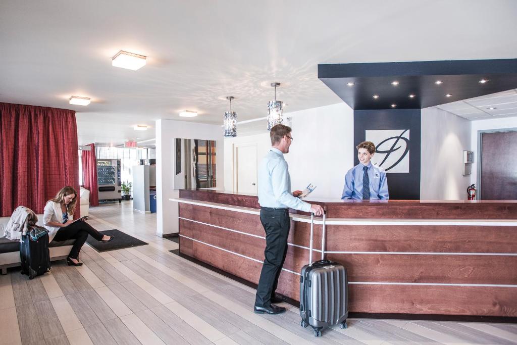 a man standing at a counter with his luggage at Le Deville par G5 in Rouyn